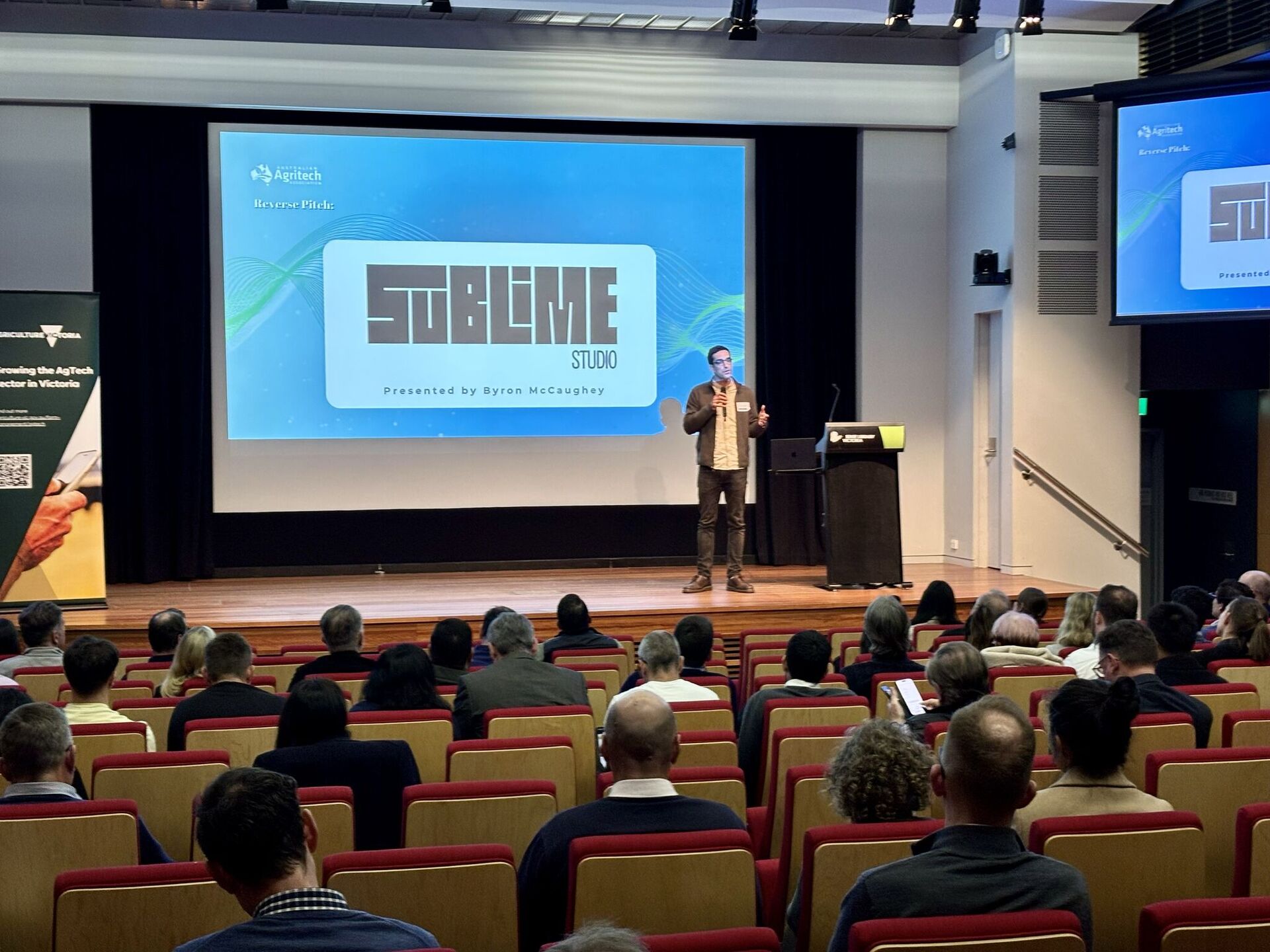 Byron McCaughey presenting a keynote on stage to a seated audience